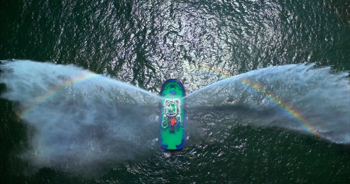 Aerial view of a tug at its handover by Udupi Cochin Shipyard, spraying water from its cannons