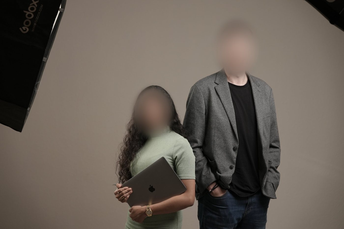 Studio portrait of two professionals, one holding a laptop