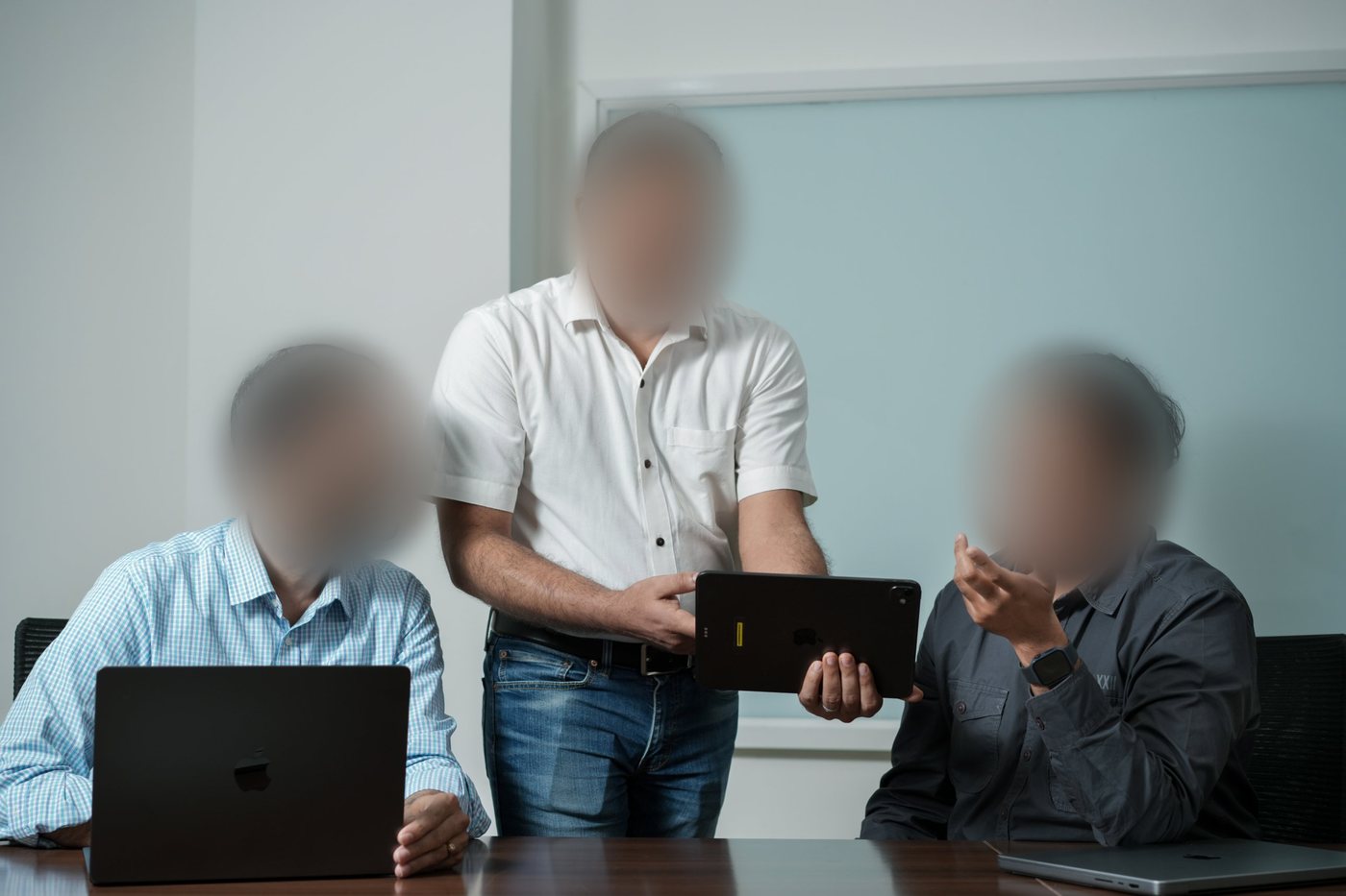 Three colleagues looking at a tablet together in a meeting room